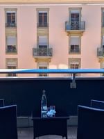 Wicker chairs by a small table on a balcony surrounding a view of buildings in Deluxe Terrace Room at Warwick Geneva
