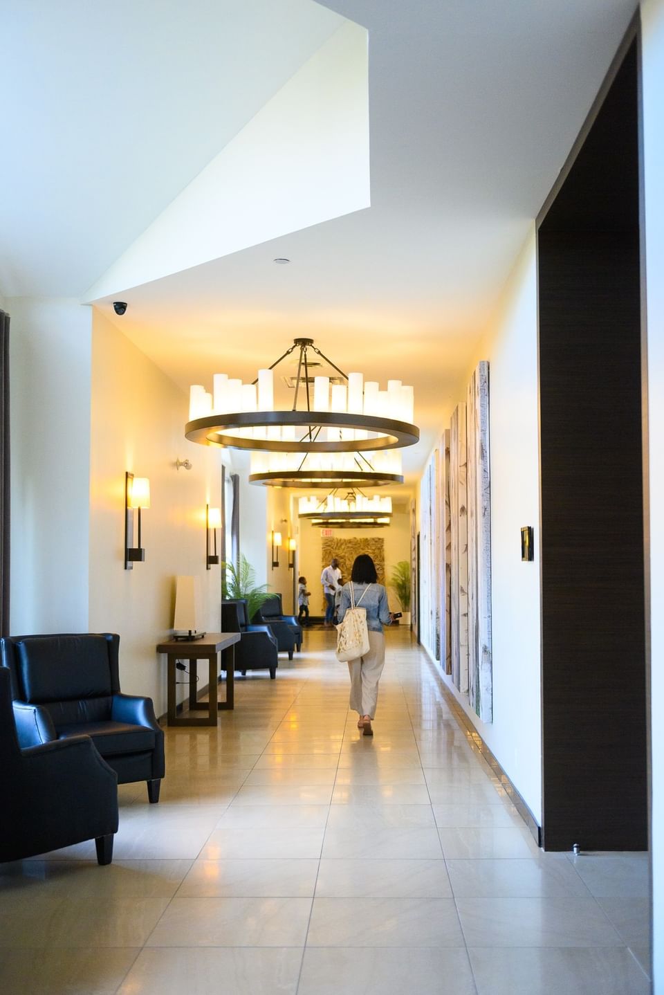 Guest walking in a hallway under large hoop chandeliers at Rodd Miramichi River, best places to stay in Miramichi