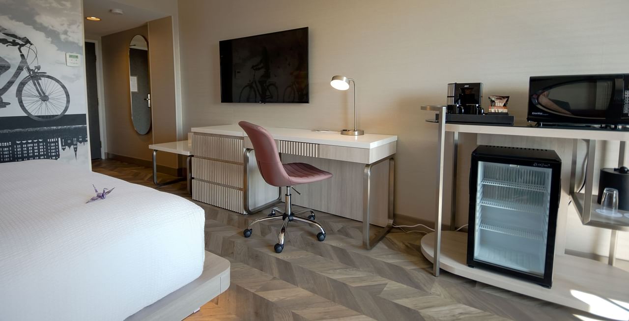 Hotel guestroom with king bed, TV, minifridge, microwave, and work table