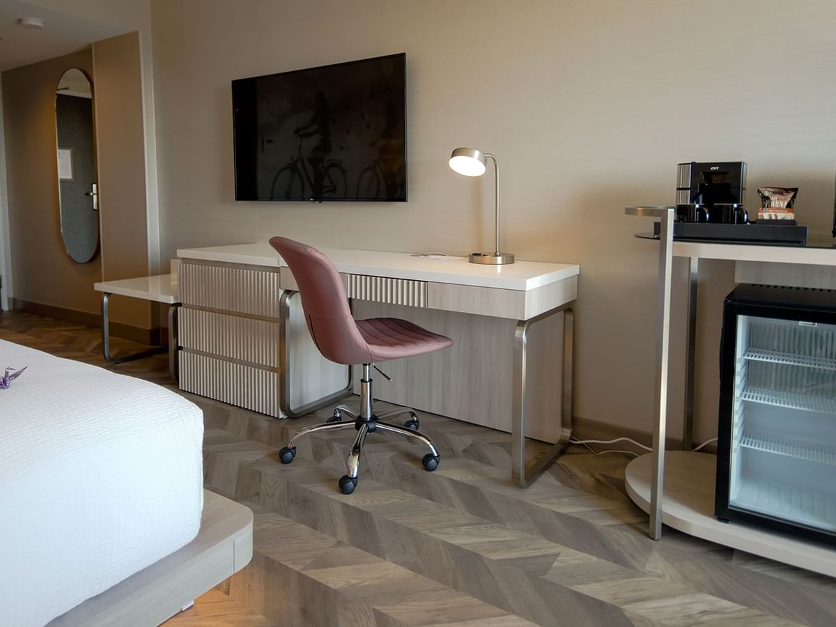 Hotel guestroom with bed, TV, work desk, microwave, mini fridge, and coffee maker.