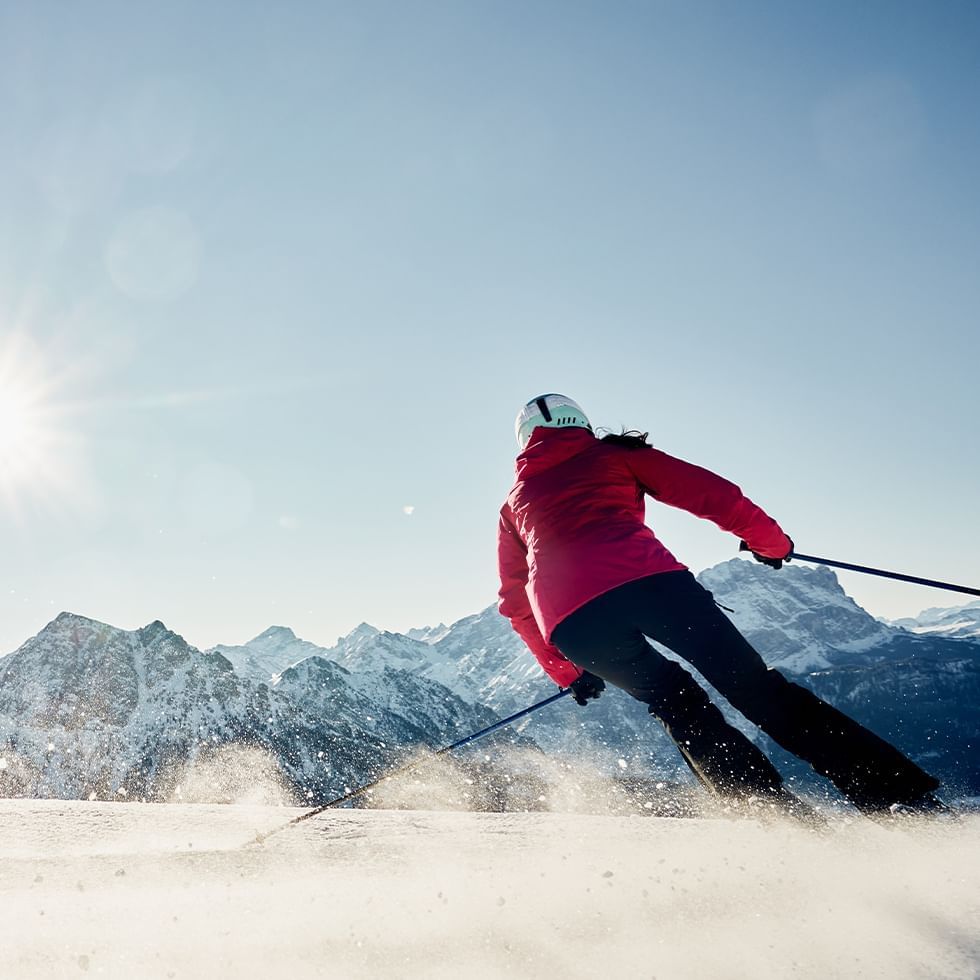 Skier descending a snowy mountain slope near Falkensteiner Hotel Sonnenalpe