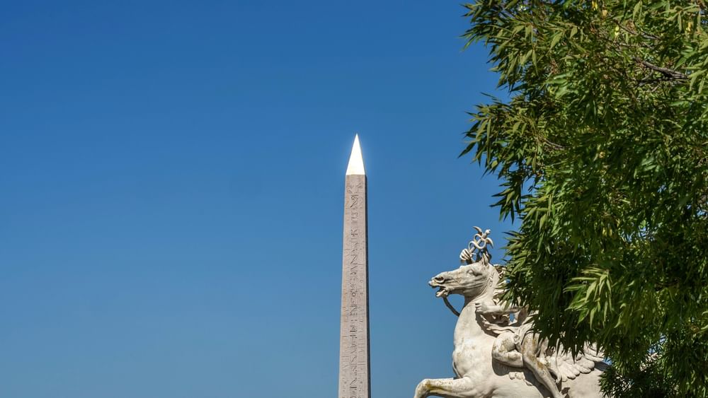 White statue of a man riding a horse with an obelisk in the background near warwick Hotels & Resort