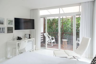 Modern Deluxe Room - 2 Queen Beds with white decor, TV, and balcony overlooking lush greenery at Le Cameleon Hotel