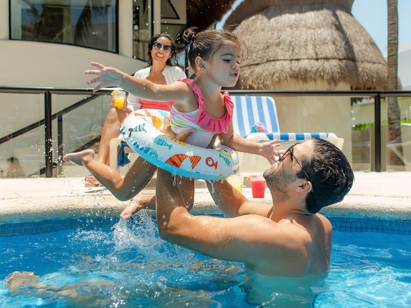 A father lift up baby in the outdoor pool at The Reef Playacar