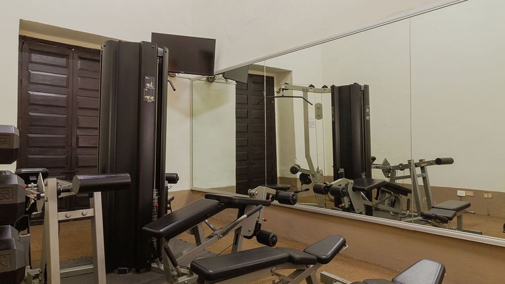 Interior of a fitness center featuring strength training equipment and a flat-screen TV at Quinta Real Puebla