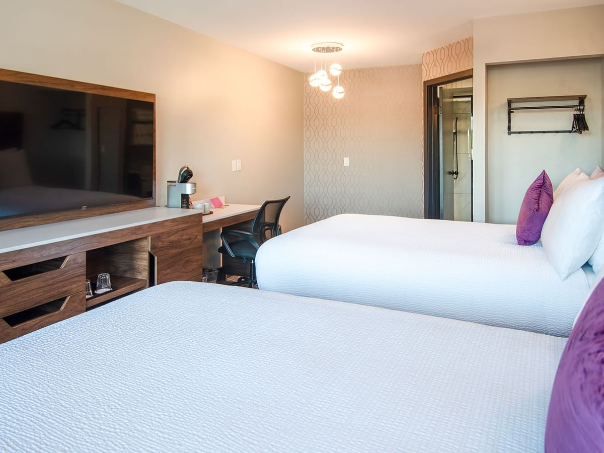 Hotel guestroom with two queen beds, flat screen TV, work desk and chair