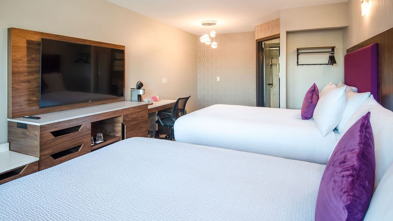 Hotel guestroom with two queen beds, flat screen TV, work desk and chair