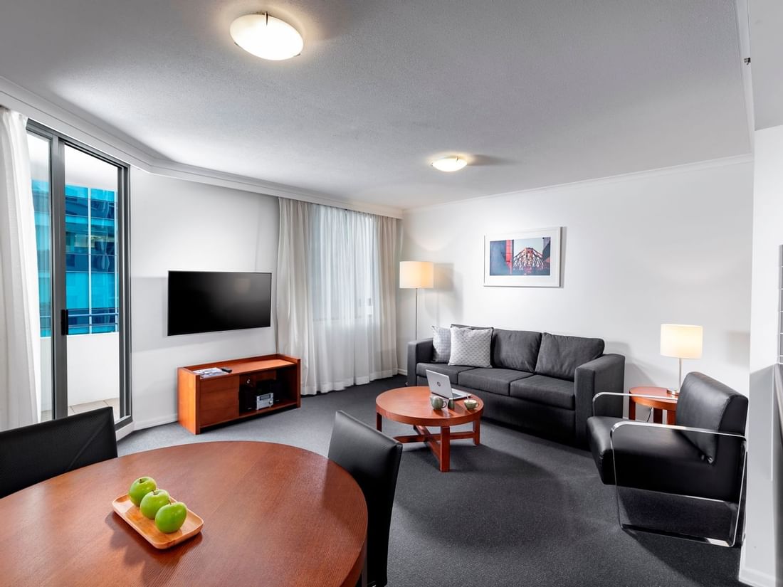 One Bedroom Apartment living area with a sofa, dining table, a TV, and a floor-to-ceiling balcony door at The Sebel Brisbane