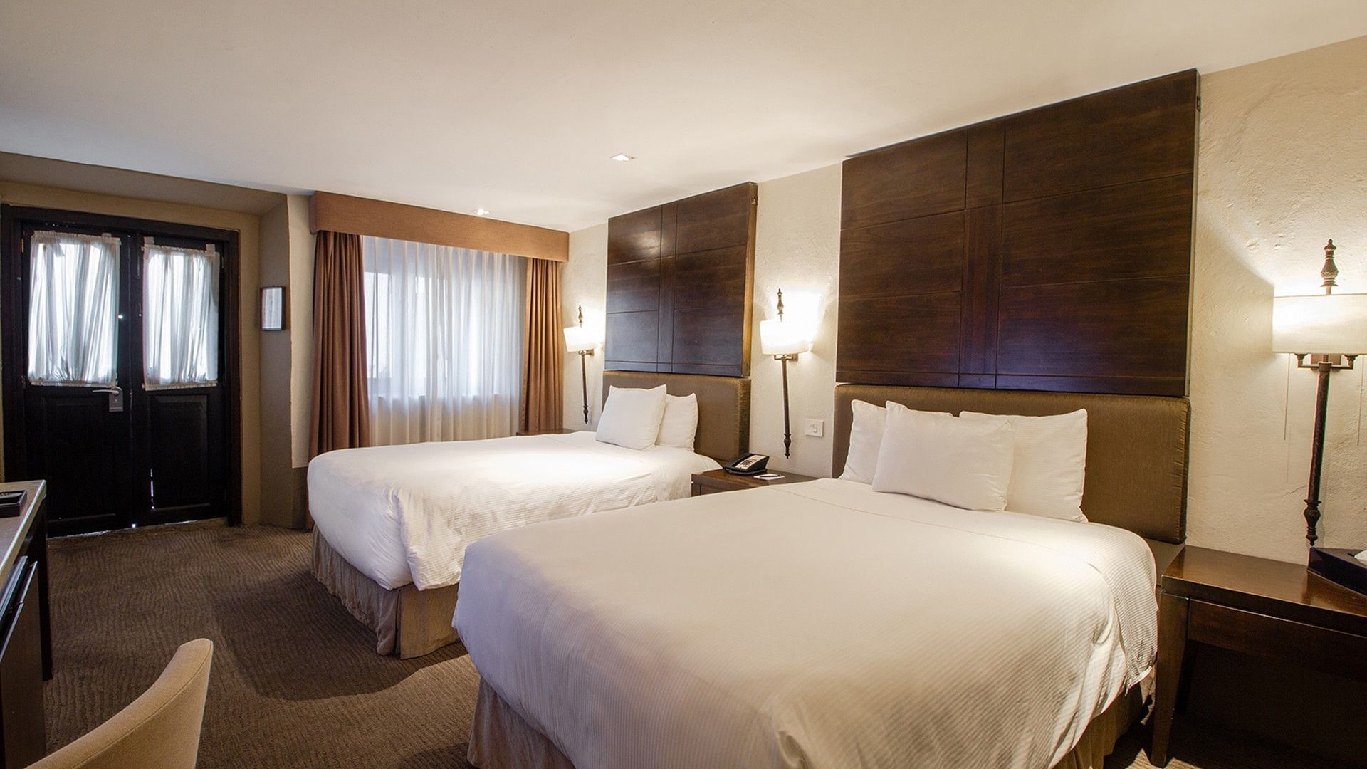 Double Grand Class Suite with two white beds featuring dark wood wall panels and classic sconces at Quinta Real Puebla