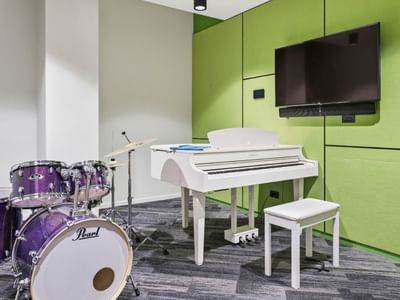 White piano and purple drums in a room with green walls and a TV at Mayoral Drive Student Accommodation.