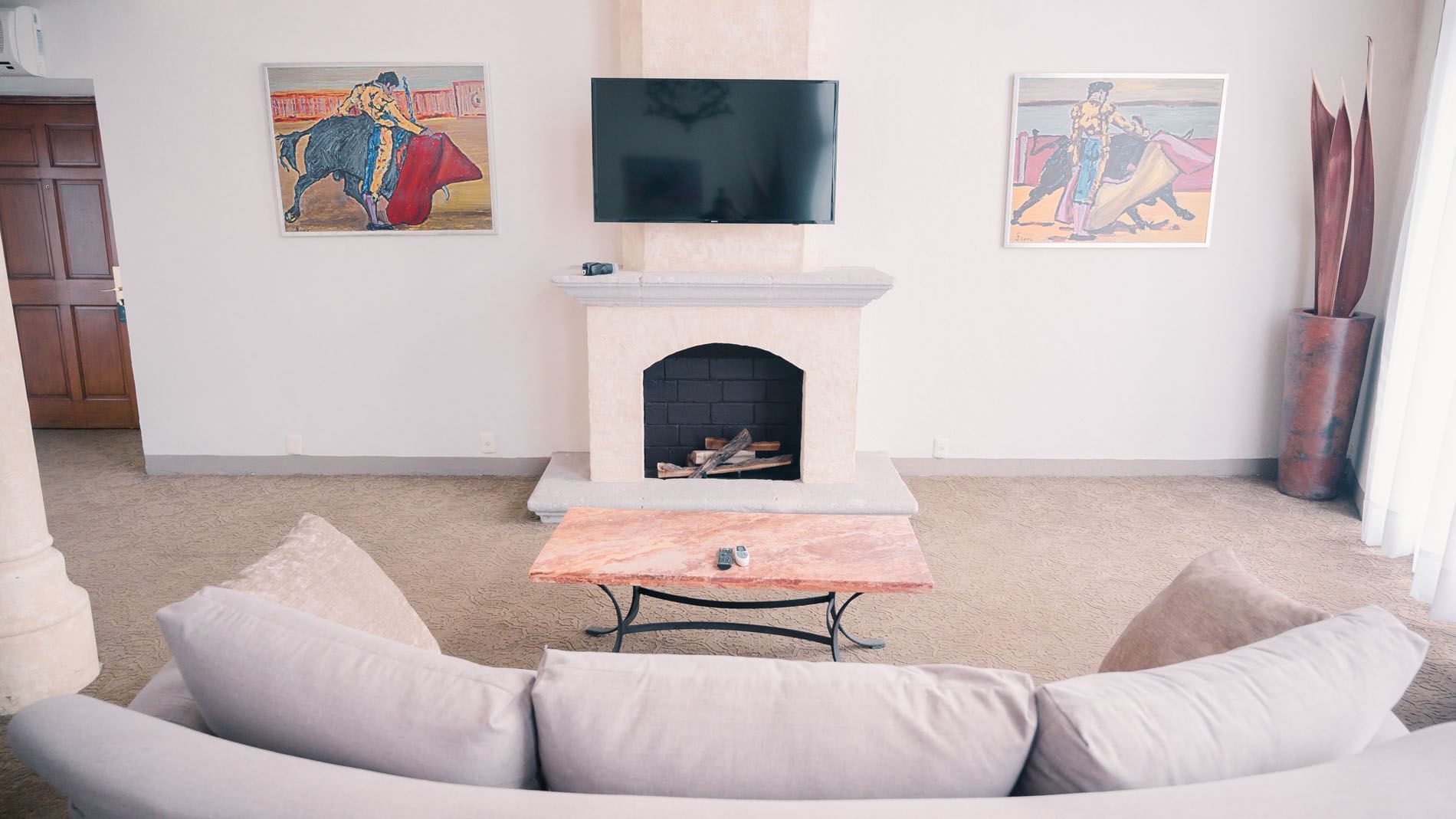 King Presidential Suite living room with fireplace, flat-screen TV, and two paintings on walls at Quinta Real Zacatecas