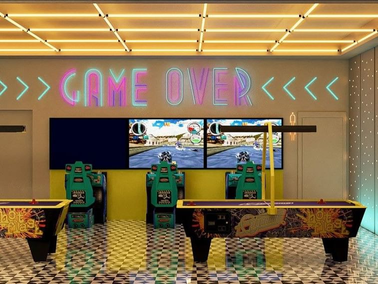 Sala de juegos vibrante en Fiesta Americana Funeeq Punta Cana con letreros de neón Game Over y mesas de air hockey