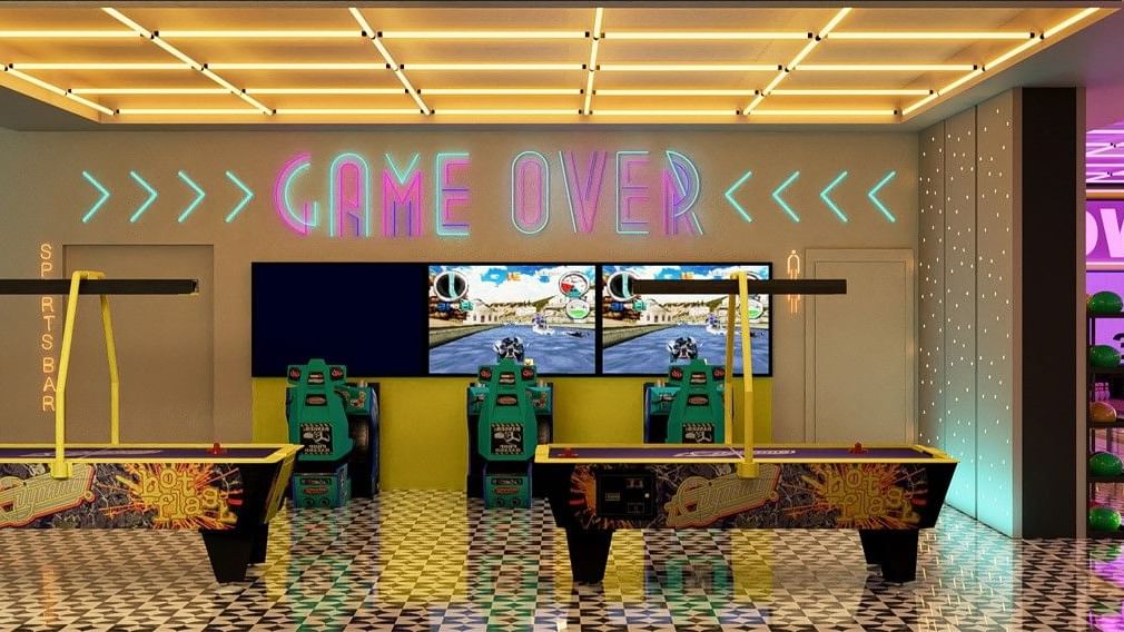 Sala de juegos vibrante en Fiesta Americana Funeeq Punta Cana con letreros de neón Game Over y mesas de air hockey