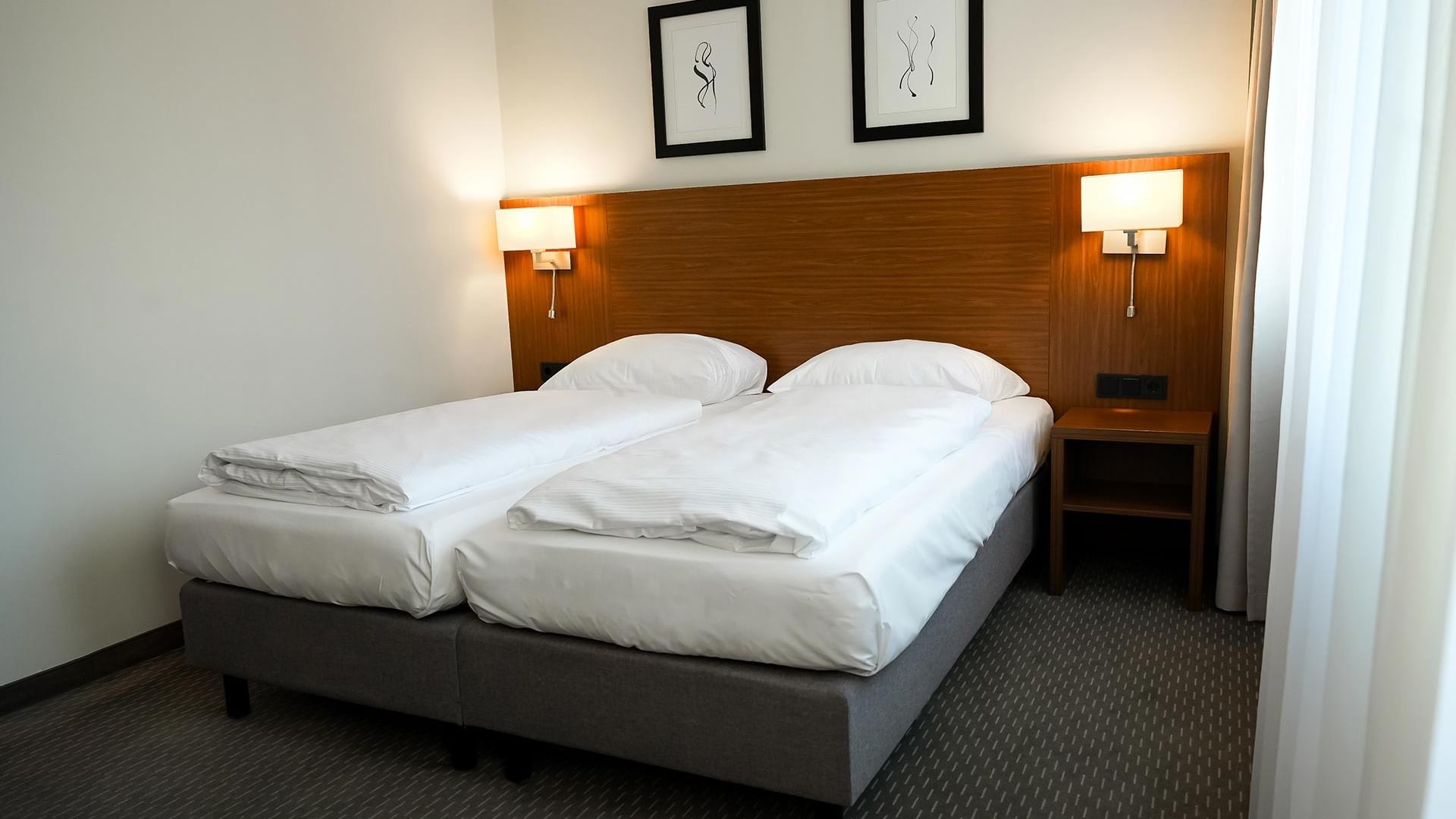 Zimmer mit zwei Einzelbetten und Wandbildern am Sylter Hof Berlin.