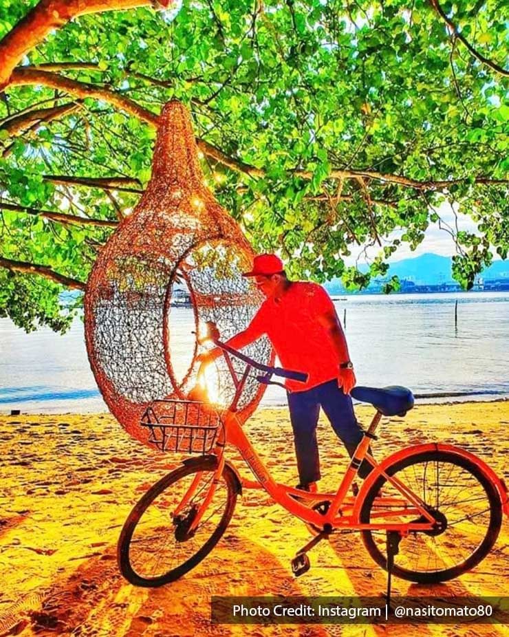 A man was taking a picture with a giant bird nest and bicycle at Pulau Jerejak - Lexis Suites Penang