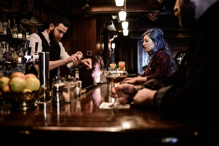 Bartender preparing cocktails in STELLA Bar with ornate woodwork at Hotel Sorrento