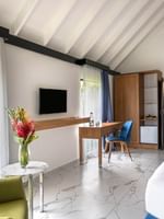 White bed with green lines facing wall mounted TV and beside seating area in Lagoon Bungalow at warwick le lagon-vanuatu