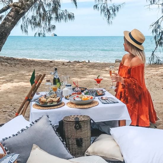 A lady is enjoying a Beach picnic at Pullman Palm Cove Resort