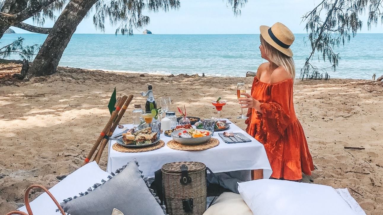 A lady is enjoying a Beach picnic at Pullman Palm Cove Sea Temple Resort & Spa
