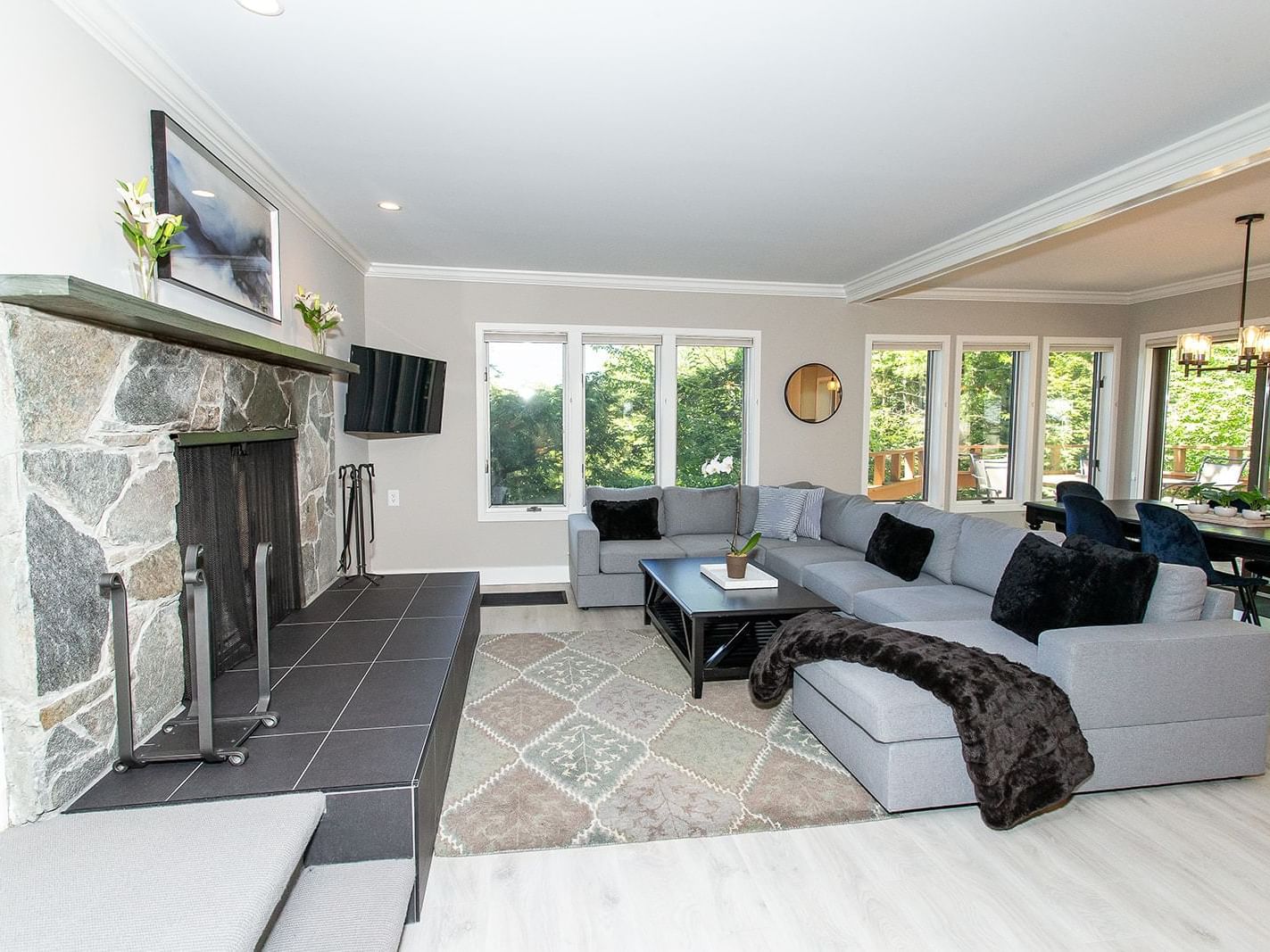 Spacious living room with stone fireplace, gray sectional sofa, and large windows at Topnotch Stowe Resort in Stowe.