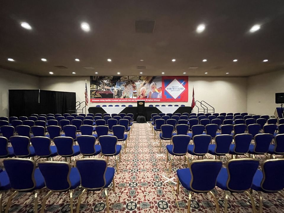 Blue chairs by a long stage under recessed lights on a patterned carpet in a meeting room at Arlington Resort Hotel & Spa