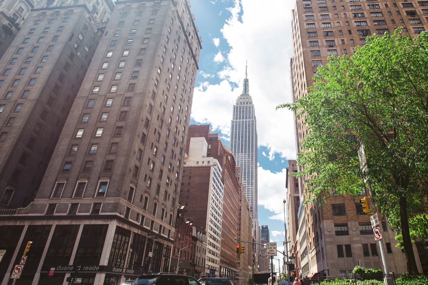 A city street with tall buildings and a view of the Empire State Building