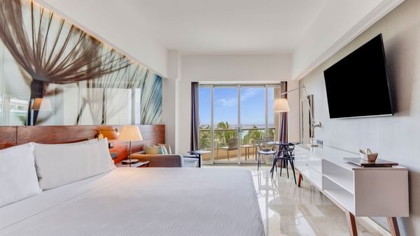King bed with arranged seating and TV in Premium Partial Ocean View room at Live Aqua Cancún