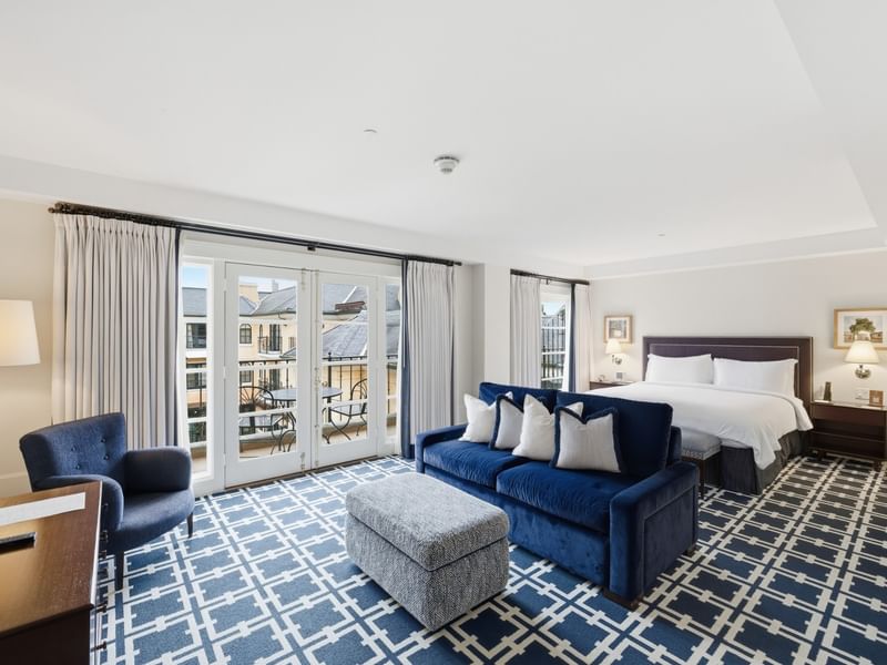 Spacious Courtyard Grand Executive King Suite with blue sofa, patterned carpet, and balcony at el PRADO Hotel.