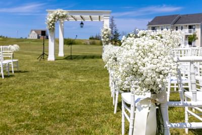 White wedding arch and chairs on the grass, highlighting prime Prince Edward Island wedding venues at Rodd Crowbush