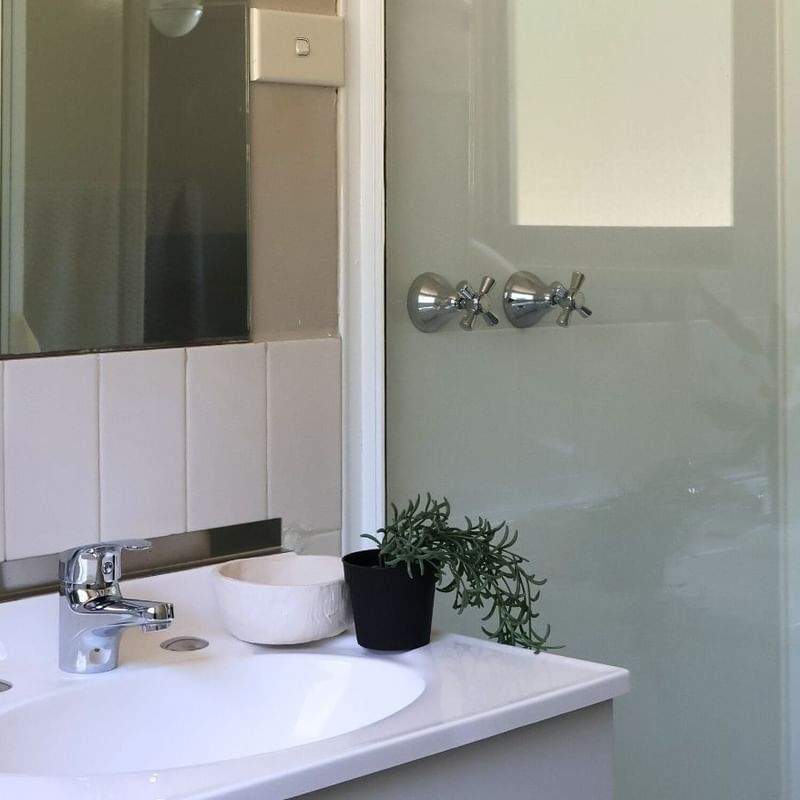 A bathroom with a sink, mirror, and shower enclosure at La Trobe University - Villas.