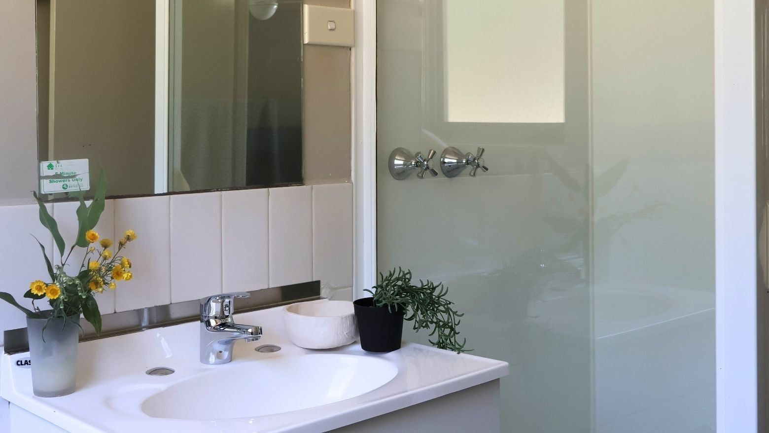 A bathroom with a sink, mirror, and shower enclosure at La Trobe University - Villas.