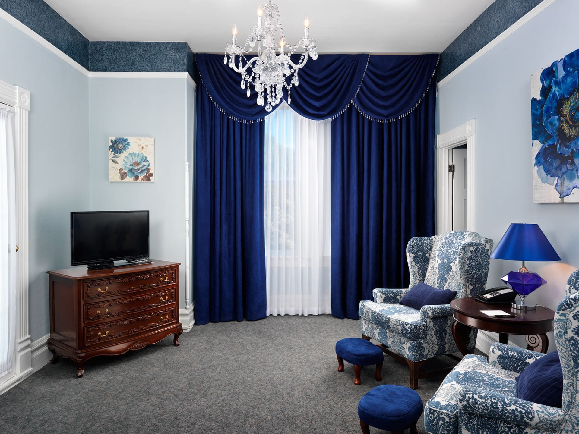 Living area with blue curtains, TV, and lounges in Queen Anne Suite at Pendray Inn & Tea House