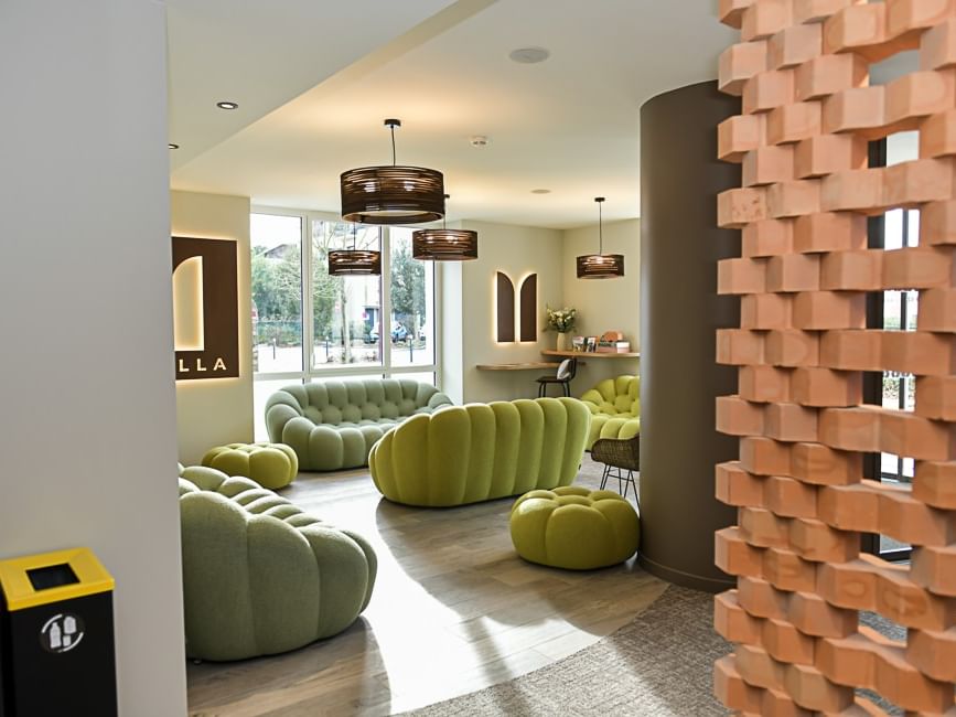 Salon moderne avec mobilier vert et mur de briques au Hôtel Rivella.