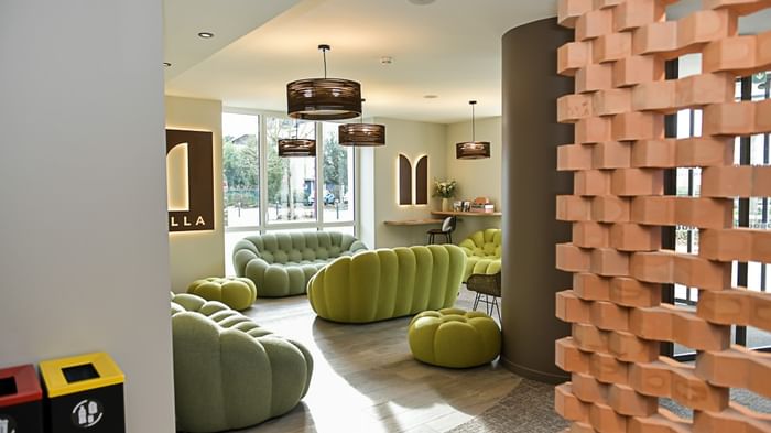 Salon moderne avec mobilier vert et mur de briques au Hôtel Rivella.