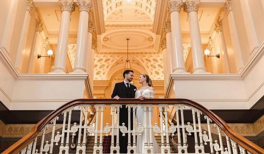 Couple posing for a photo in majestic grand staircase at Fullerton Group