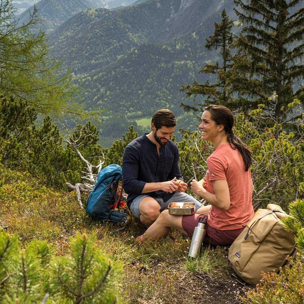 Coppia in viaggio con zaini su un sentiero montano per l'offerta Coolcation a Schladming.