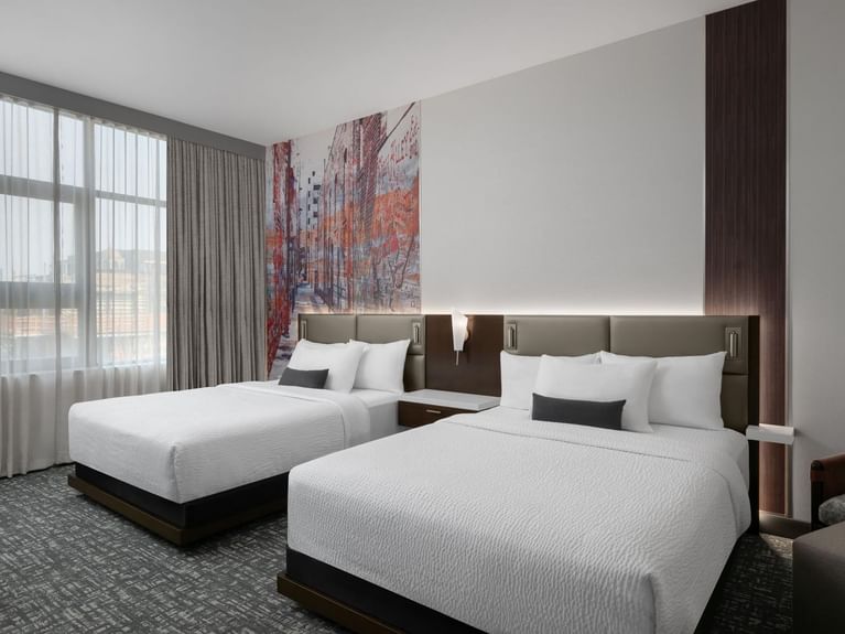 Capital Double Queen room with cozy double beds and an abstract mural of a bustling urban streetscape at Hotel 43 Boise