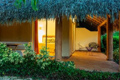 Cozy bungalow at La Casita by the Hub, featuring a thatched roof, private patio, and lush tropical scenery