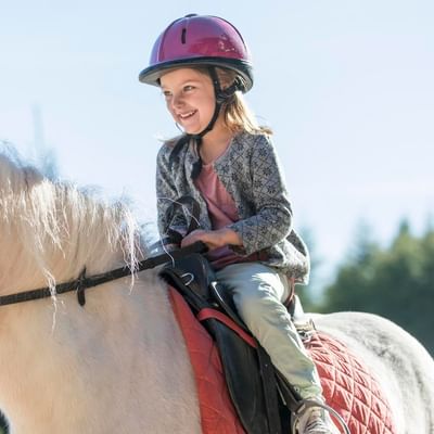 A kid enjoying horse riding near Falkensteiner Hotels