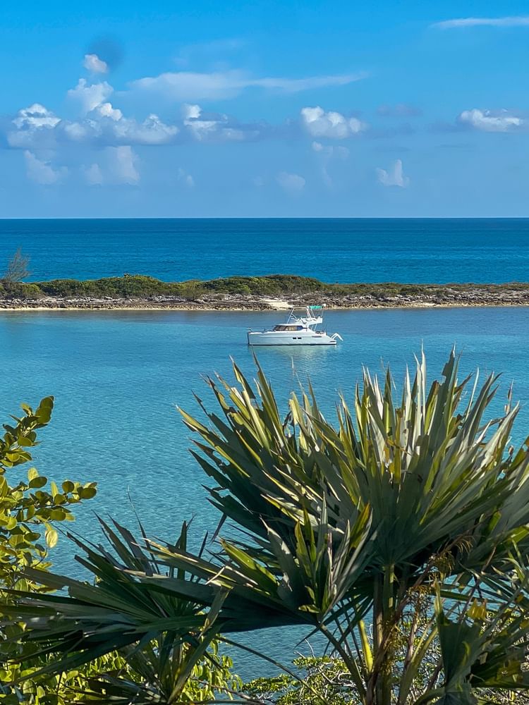 Nassau with White boat on a clear blue bay by a rocky islet, under a sunny sky near Warwick Hotels & Resort