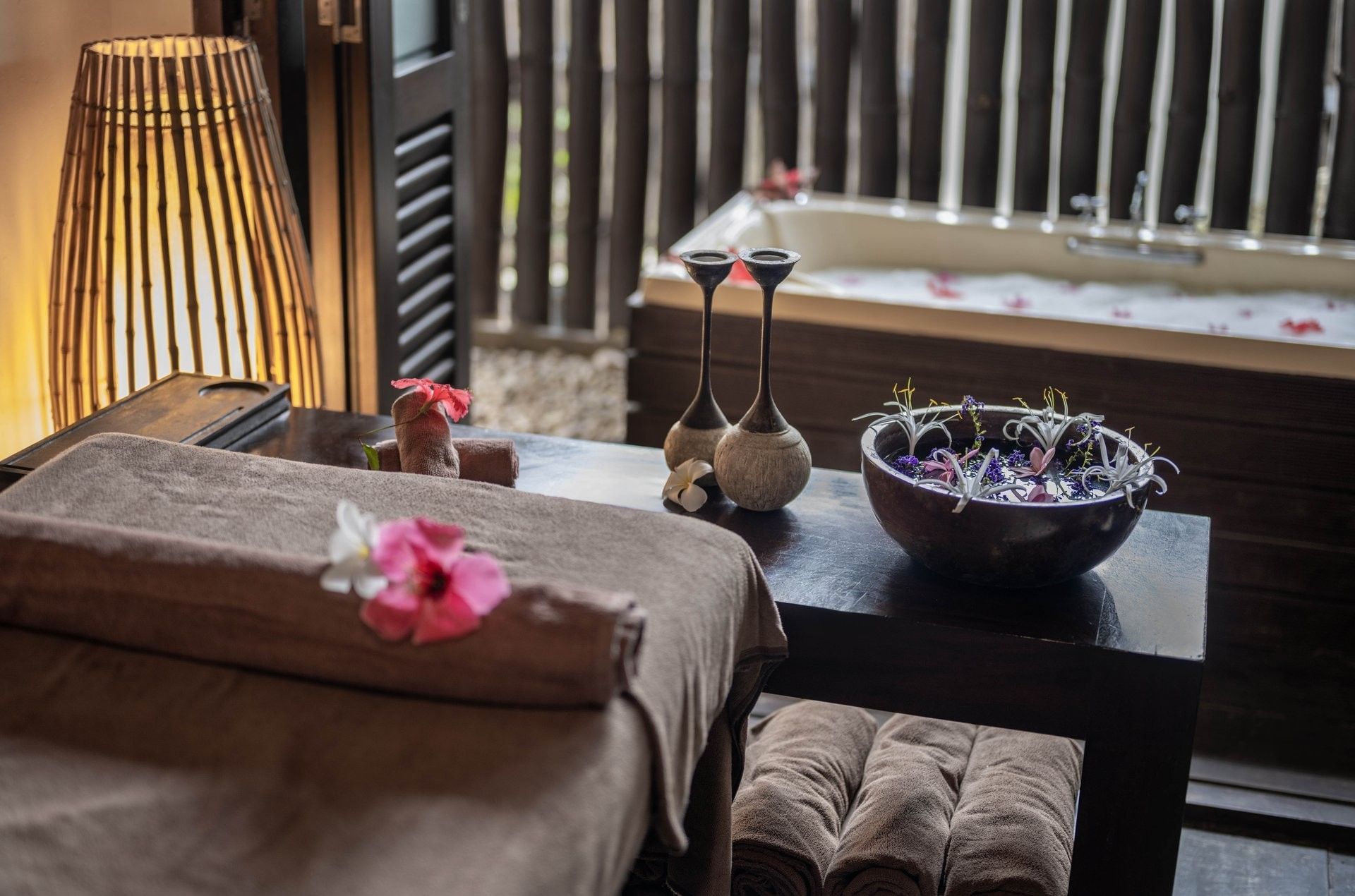 Calm spa room with a massage table & fresh flowers, and a water-filled tub in the back at warwick le lagon-vanuatu