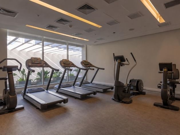 Centro fitness con cintas profesionales y bicicletas estáticas junto a ventanas en Veranda Hotel
