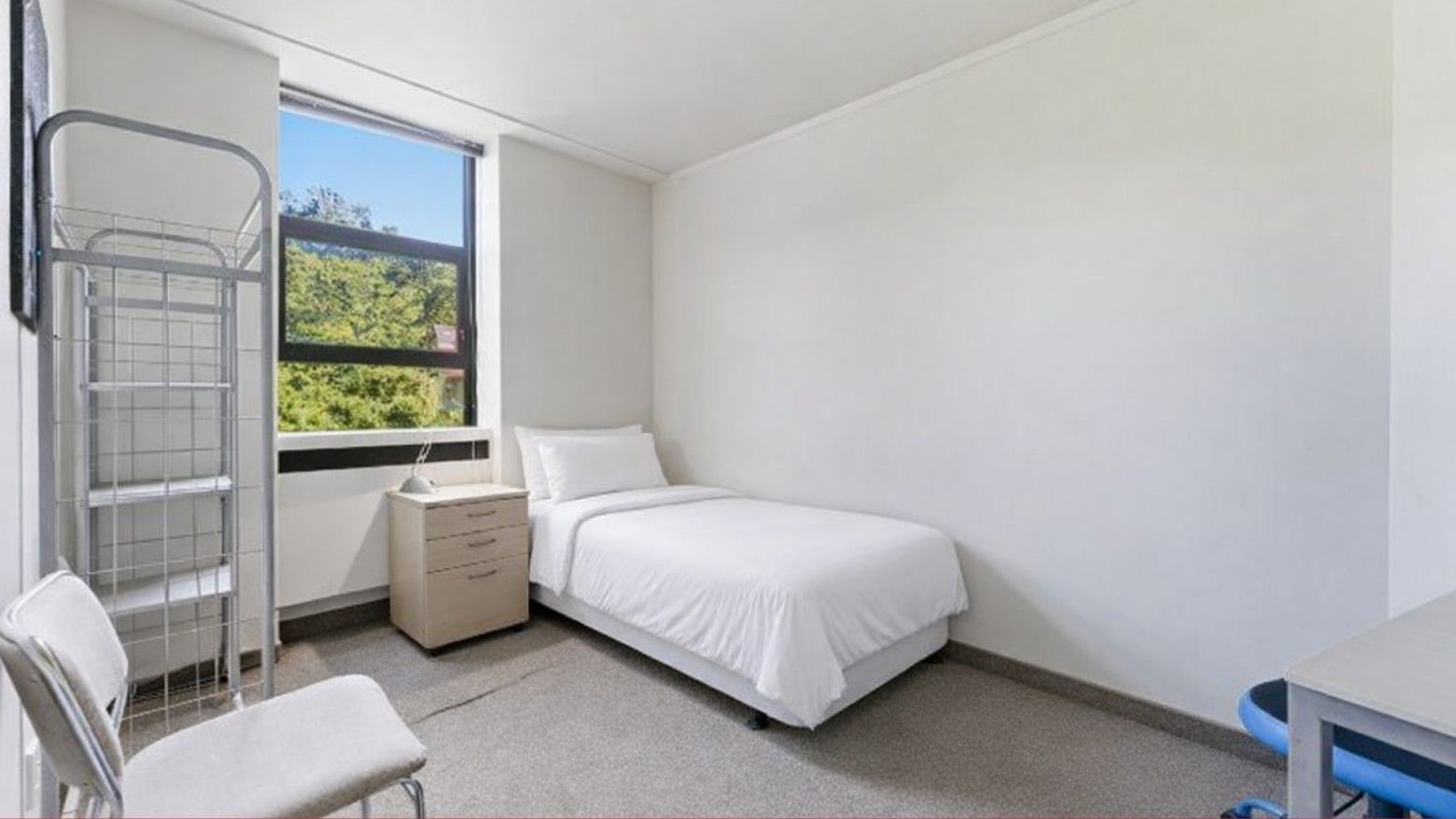 White bed, chair, desk, and window in a room at UniLodge Stafford House.