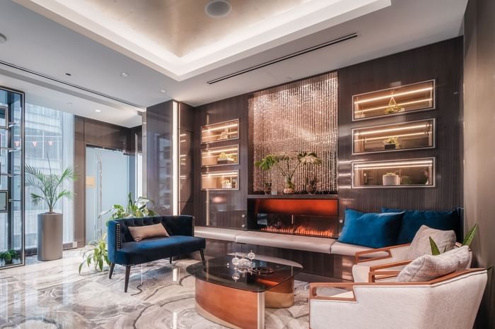 Modern lobby at the Xylia Spa with marble floor, blue couch, coffee table, chairs, fireplace, and display cases with plants.