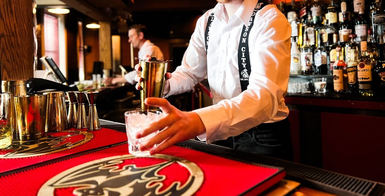 Bartender preparing a drink in a restaurant at Midnight Sun, a Coast Hotel