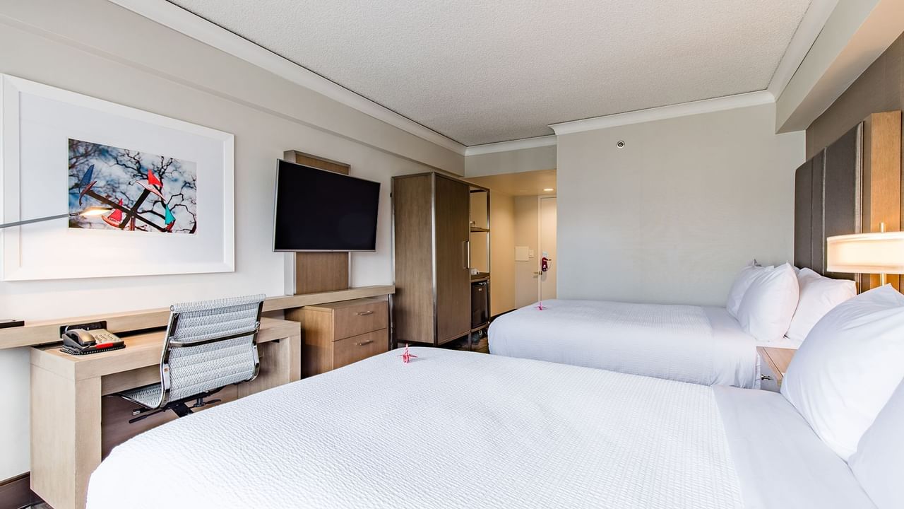 Accessible hotel guestroom with two beds, TV, and desk
