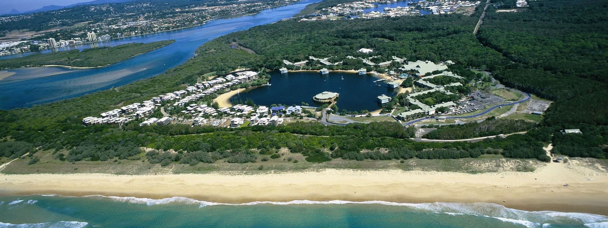Aerial view of coastal area with beaches, lagoon, greenery, and a residential area near Novotel Sunshine Coast Resort