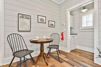 Cozy dining nook with black chairs, round wooden table, white mugs, and art on shiplap walls by Cottages at Laurel Brooke