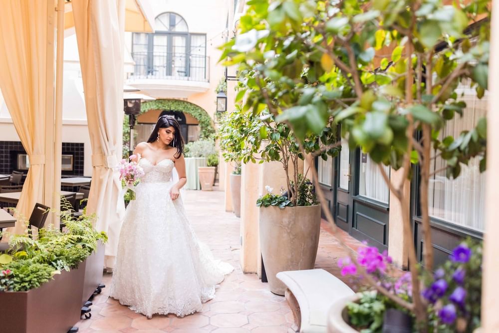 Beautiful bride walking through a charming outdoor patio at El Prado Hotel