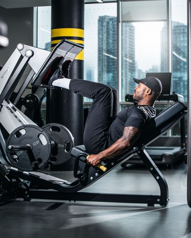 Man exercising on leg press machine in fitness center with city views